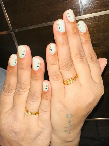 Art on natural nails. This simple design features a creamy white base with a few small, colorful dots at the cuticle.