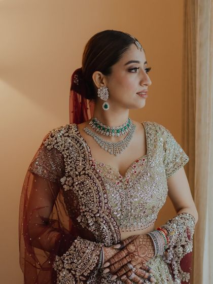 A pensive moment by the window. This profile shot highlights the contouring and the sleek ponytail, a modern hairstyle choice for a traditional outfit.