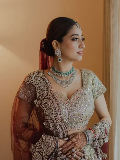 A pensive moment by the window. This profile shot highlights the contouring and the sleek ponytail, a modern hairstyle choice for a traditional outfit.