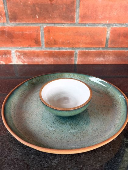 A simple and elegant chip and dip server made by a student. The contrast between the earthy green glaze on the plate and the white glaze in the bowl is beautiful.