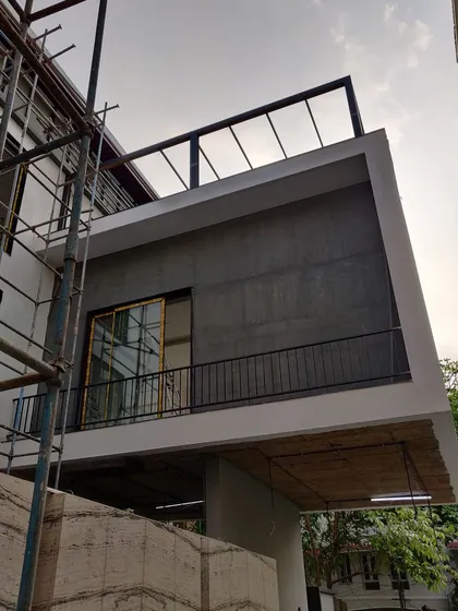 The "before" shot, showing the same residential facade during the construction phase with exposed concrete and scaffolding.