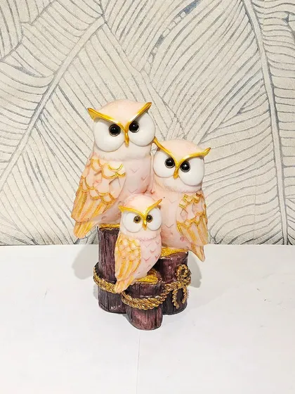 An owl family perched on logs, shown here in a lovely pink and gold finish.