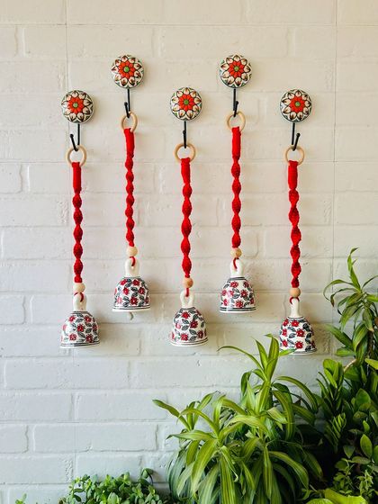 A set of five 'Cherry' macrame ceramic bells in a bold red color. These handcrafted pieces are perfect for making a statement and adding a pop of color to your decor.