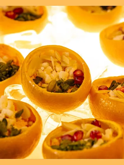 Delight in our "Cosmic Dawn," a unique orange-flavored dessert topped with nuts and pomegranate seeds, served elegantly in its own citrus shell.