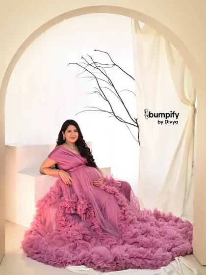 A vision in pink. This mom-to-be is wearing a magnificent ruffled tulle gown that fills the frame, creating a soft, dreamy, and utterly glamorous maternity portrait.