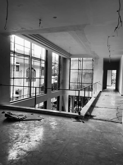 The bare shell of a double-height space, with scaffolding visible through the large window openings. This shows the volume and light potential before interior work begins.