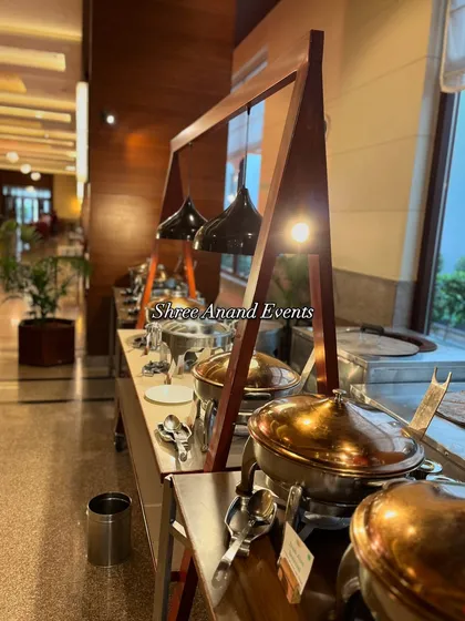 A detailed shot of the serving dishes on the modern buffet line. The combination of stainless steel and brassware under focused lighting creates an appealing and professional look.