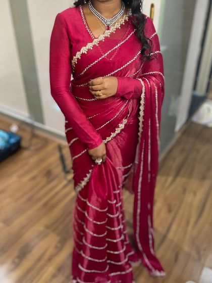A modern and chic look with a deep red organza saree. The draping is kept clean and simple to let the fabric and the full-sleeve blouse shine.
