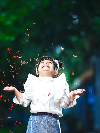A moment of pure joy as she throws flower petals into the air, her face lit up with happiness.