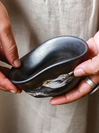 An organically shaped bowl, with a smooth black interior contrasting the raw, layered exterior created through saggar firing. This piece is a testament to the beauty that grows when curiosity meets shared knowledge.