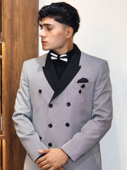 A classic double-breasted suit in a grey pinstripe. The black lapels and buttons add a modern touch, making it a versatile piece for both formal and semi-formal events.