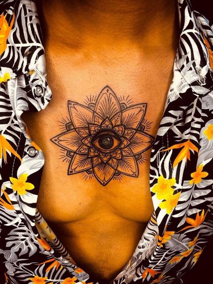 This chest piece features a third eye at the center of a geometric mandala lotus. It's a powerful symbol of intuition and spiritual awakening. The placement on the sternum makes it a very personal and significant tattoo.