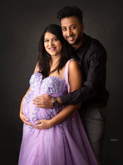 This couple looks so happy and in love. The mom-to-be is in a beautiful lavender gown while her partner holds her close.