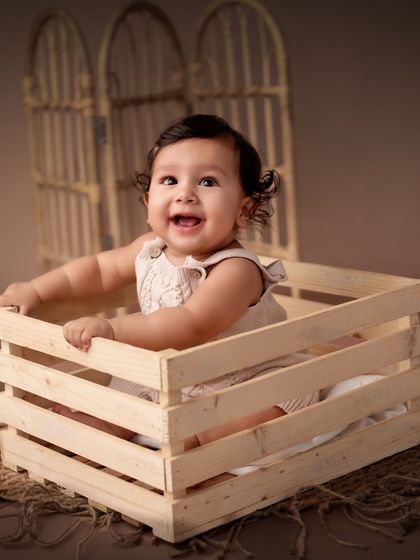 Another angle of a happy baby boy in a wooden crate.