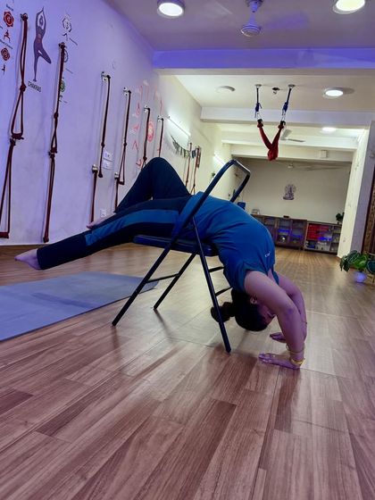 Finding the perfect alignment in a chair-supported backbend, with a yoga mat for extra cushioning.