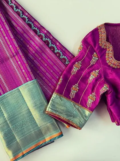 A flat-lay of a custom blouse and saree combination. This magenta blouse features unique embroidery on the sleeves, designed to match the pattern of the silk saree.