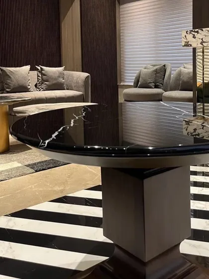 A detail shot focusing on the material contrast in the Juhu apartment. The glossy black marble of the dining table stands out against the graphic, striped floor, creating a visually dynamic composition.