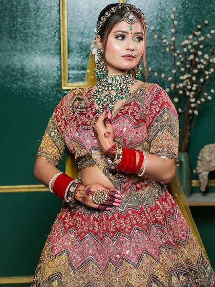 A multi-colored chevron lehenga, similar to a previous look but styled with heavy green jewellery for a different effect.