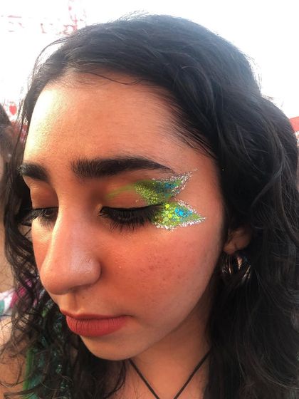 A close-up of the green and silver butterfly wing eye glitter. You can see the fine details and the blend of colors.