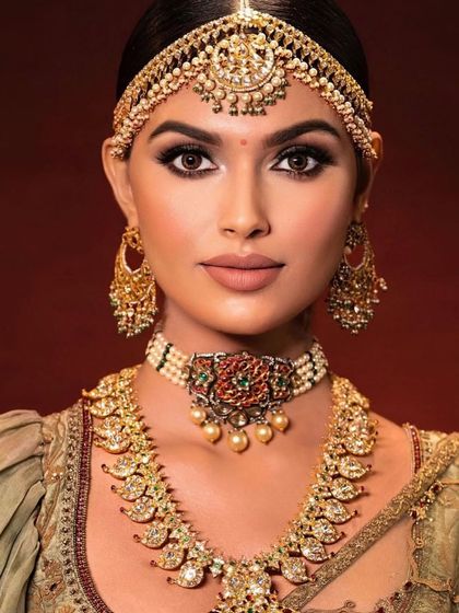 A closer look at a regional bridal style. The makeup features a classic winged liner and a matte, neutral lip to balance the ornate gold jewellery and traditional headpiece, creating a look of timeless grace.