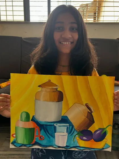 The proud student holding her impressive still life painting. We use poster colours to practice rendering light, shadow, and reflections for the exams.