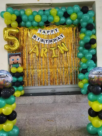 A Minecraft theme birthday decoration for a 5th birthday. The green, yellow, and black balloons match the game's aesthetic, complete with themed character and game-world balloons.
