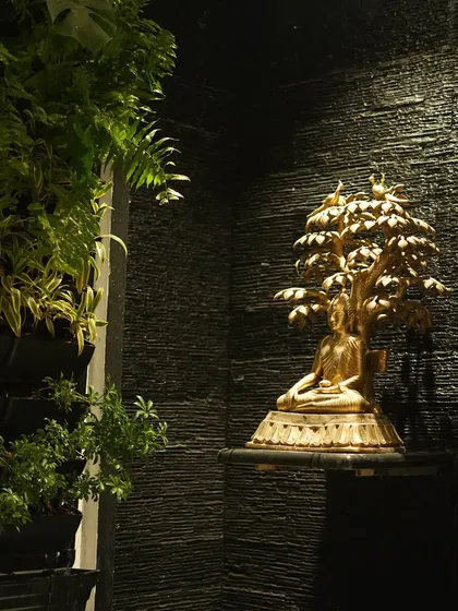 Another angle of the golden Buddha statue, showing its placement next to a lush vertical garden, creating a beautiful contrast of textures.