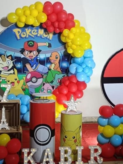 A Pokemon themed birthday setup with a circular backdrop, character props, and themed pedestals.