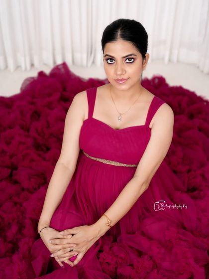 A stunning high-angle shot of a mother-to-be in a wine-colored ruffled gown, looking directly at the camera.
