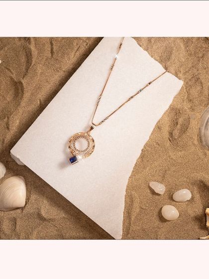 An Italian chain pendant with a circular motif and a single blue stone, offering a pop of color.