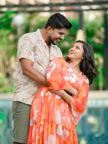 A relaxed and stylish poolside shoot. The lush green surroundings and calm water provide a beautiful, resort-like setting for casual and romantic couple photos.