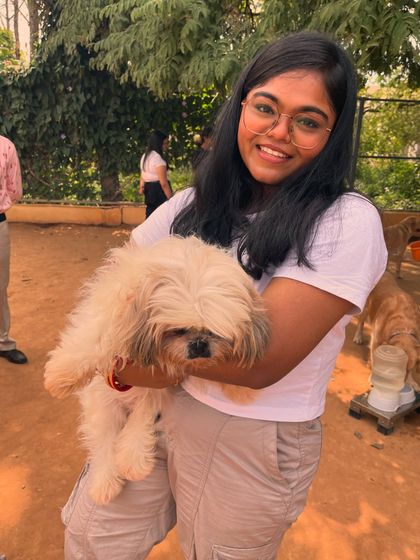 A smiling visitor holds a cute Shih Tzu, showcasing the hands-on experience at our park.