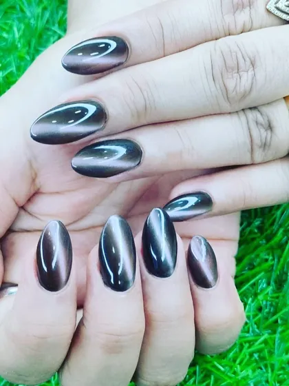 A close up of this stunning cat-eye nail art in a deep, glossy brown. The magnetic effect creates a beautiful light-reflecting band across the nail, giving it a unique, gem-like quality. I shape each nail extension carefully to achieve this perfect oval look.