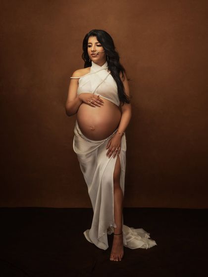 A similar pose that captures the serene and powerful essence of her pregnancy, with the white drape flowing elegantly.