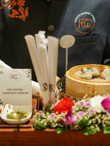 Delicately steamed Veg Water Chestnut Dimsum presented on a floral-adorned tray. This offering highlights our Pan-Asian menu, served with accompanying chili and soy-based dipping sauces.