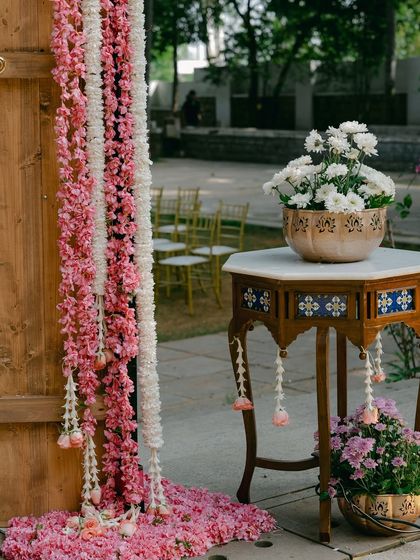 A close-up of the floral decor on the entrance arch, featuring cascading garlands of pink and white flowers.