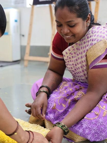 A smiling team member prepares flower garlands.