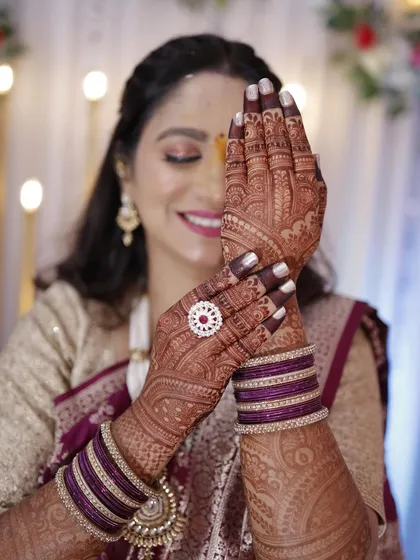 A happy client showing off her gorgeous, dark engagement mehendi stain. The color beautifully complements her outfit and jewelry.