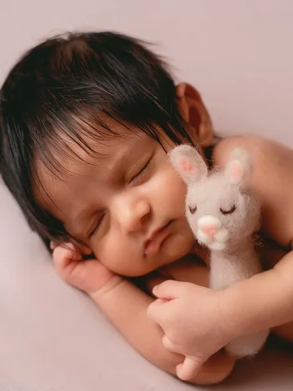 Adding a tiny, soft toy can create a sweet and sentimental portrait. Here, the baby is cuddling with a felted bunny, adding a touch of tenderness to the shot.