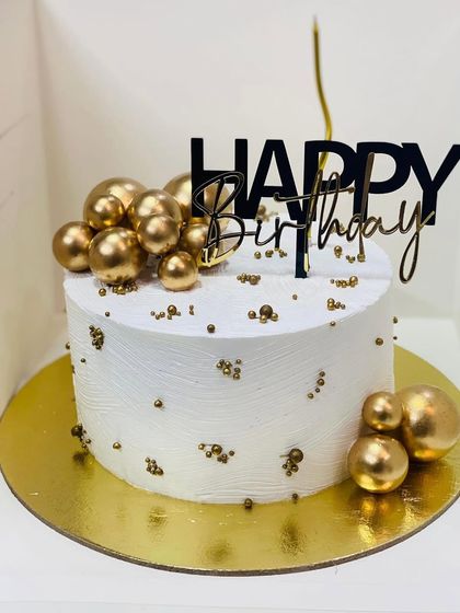 A simple yet elegant white and gold birthday cake, perfect for a minimalist celebration.