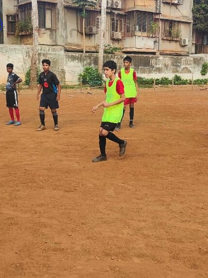 A player prepares to make a move during a football drill. Our training on traditional grounds builds resilience and fundamental skills that are essential for any aspiring footballer.
