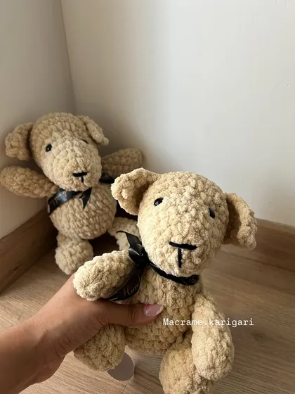 This soft, cuddly dog toy is made from chunky yarn, making it extra plush and safe for little ones. It features a simple black ribbon for a touch of charm.