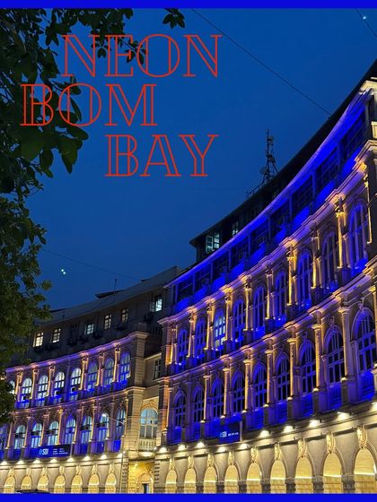 A building in South Bombay bathed in blue neon light, creating a futuristic glow on its classical facade.