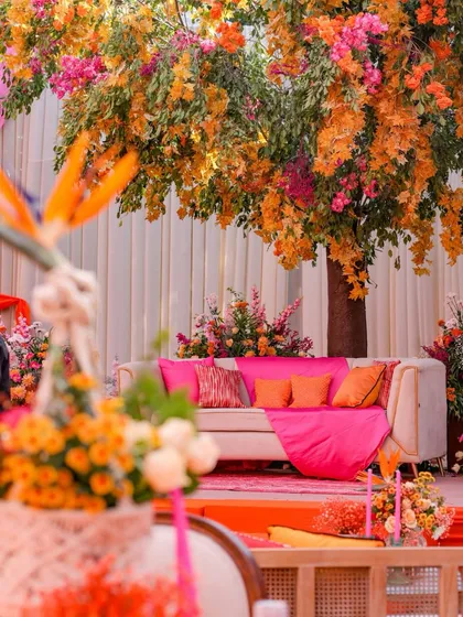 A cozy lounge sofa set under the blooming floral tree, with bright pink and orange cushions adding a pop of color.