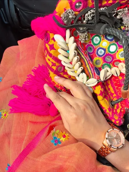 A detail shot of my Poila Boishak look, focusing on the colorful, handcrafted bag with mirror work and shells, paired with my orange embroidered saree.