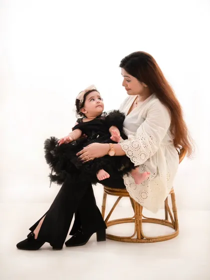 A beautiful mother and daughter portrait. The simplicity of the white background and rattan chair allows the loving gaze between them to be the central focus.