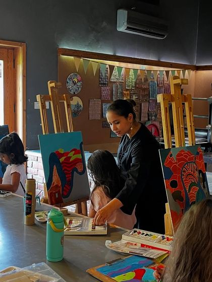 An instructor provides guidance to a student, helping her with composition and color choices for her landscape painting.