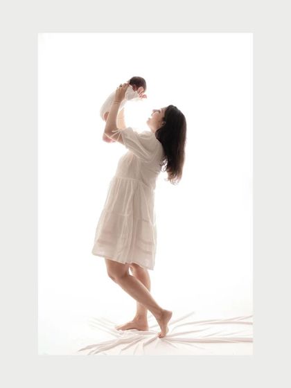 A mother joyfully lifts her newborn baby in a beautiful silhouette against a bright white background. This is a celebration of new life and love at first sight.