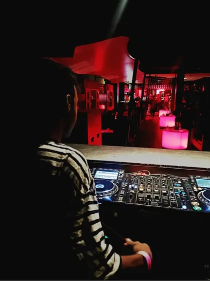 In the zone, surrounded by the warm red glow of the club. This is my element, finding the perfect tracks to match the mood of the venue.