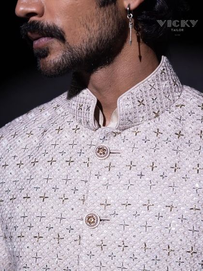 The fine details of our craftsmanship. This close-up on the collar and buttons of an embroidered jacket reveals the quality and precision that go into every garment.